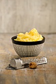 Mashed potatoes in bowl with grater at side