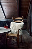 Wooden chair with fur pillows on balcony with beverage on wooden table