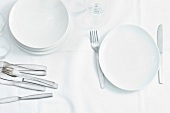 Plates, knifes, forks and glasses on white background