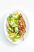 Romaine lettuce with peanuts and chicken satay in serving dish