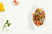 Fried chilli rice in serving dish and vegetables on white background