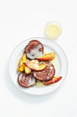 Chocolate pancakes with slices of peaches on plate