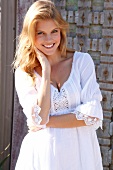 Portrait of beautiful blonde woman wearing white tunic blouse, smiling