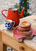 Ausgezogene (Bavarian-style doughnuts) next to a coffee cup and an enamel jug on a wooden table (Germany)