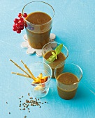 Three glasses of juice and one glass with skewers in it on blue background