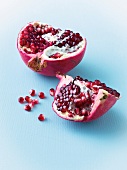 Halved pomegranate with seeds on blue surface