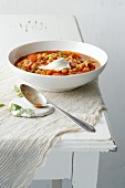 Bowl of chick pea and tomato soup with spoon on table