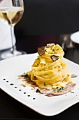 Stack of tagliatelle with autumn truffles and marinated veal tongue in plate