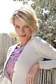 Portrait of pretty blonde woman with short hair wearing top and white cardigan, smiling