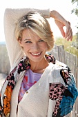 Portrait of beautiful blonde woman wearing white sweater and colourful scarf, smiling