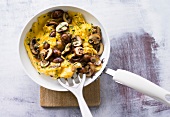 Scrambled eggs with mushroom in pan on wooden platter