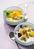 Orange yogurt with cashew nuts and fruits salad in serving bowls