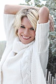 Pretty blonde woman wearing white turtleneck sweater standing with arms on head