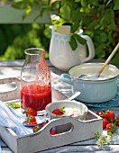 Milchreis mit Erdbeersauce auf Tablett auf Tisch im Garten
