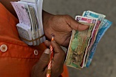 Man counting notes and writing figures on hand, Colombo, Sri Lanka