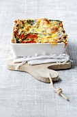 Spinach lasagna gratin with tablecloth on wooden serving board