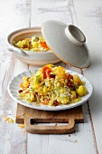 Plate and bowl of veggie pilaf on wooden serving tray