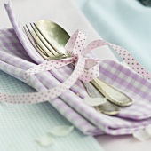 Close-up of tied checked cloth napkins and cutlery with ribbon