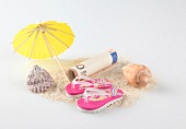 Rolled bills, shell, flip-flops, umbrella on sand on white background