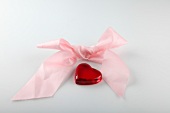 Close-up of pink ribbon with heart on white background