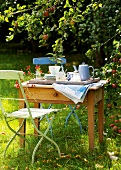 Landküche, Holztisch im Garten mit Tablett mit Geschirr darauf