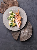 Veal chop with pretzel crust and potato watercress salad on wooden board