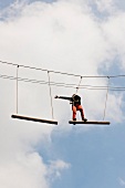 Man taking high ropes course in amusement park at Dankern Leisure Centre Castle, Germany
