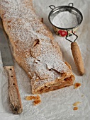 Apple strudel powdered with icing sugar and sieve and knife