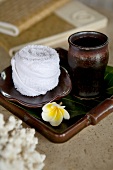Close-up of cup, plumeria and towel place in tray for spa 