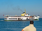 Man at promenade looking at ferry in sea, Izmir, Aegean Region, Turkey