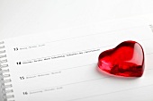 Red glass heart on calendar with date of 14th February
