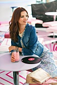 Frau in Jeansblazer, draußen, sitzt im Café, mit Milchshake, Denim-Look