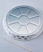 Disposable aluminium tray and wooden skewers on gray background