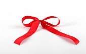 Close-up of red satin bow on white background