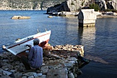 View of fisherman painting boat near Simena and Sarcophagus in Lycia, Aegean, Turkey