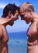 Two shirtless men with muscular build standing head to head, screaming