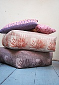 Various colourful cushions stacked on wooden floor