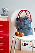 Retro look tote bag made from old jeans with leather handles on white chair