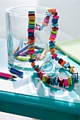 Chain made of colourful pencil stubs and crayons in glass