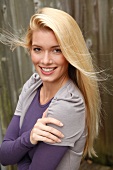 Portrait of beautiful blonde woman with long hair wearing purple top, smiling