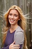 Portrait of beautiful blonde woman with long hair wearing purple top, smiling