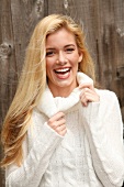 Portrait of beautiful blonde woman with long hair in white turtleneck sweater, smiling