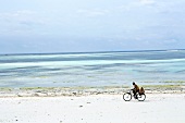 Man cycling on beach of Zanzibar, Tanzania, East Africa