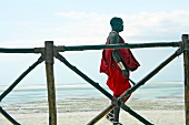 Man walking alongside bamboo fence on beach of Zanzibar, Tanzania, East Africa