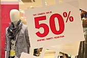 Red sign of 50% discount with mannequin in the shop window