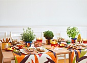 Laid table decorated with fresh herbs in a pot and colourful table runners