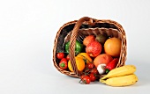 Obstkorb, umgekippter Bastkorb mit Obst und Gemüse