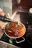 Pouring red wine in braised beef and stir fried vegetables in pan