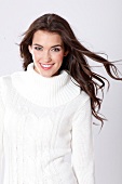 Portrait of beautiful woman with dark long hair wearing white turtleneck sweater, smiling