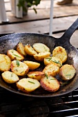 Close-up of roasted potato halves in pan with rosemary